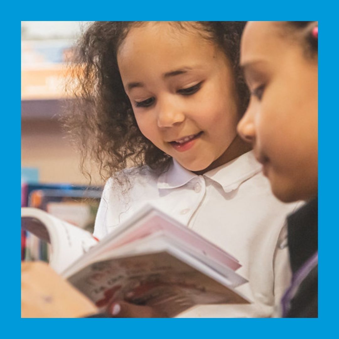A photo of two children enjoying a book together