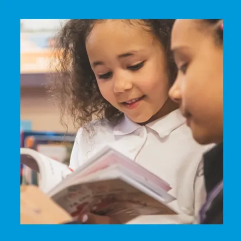 A photo of two girls enjoying a book together.
