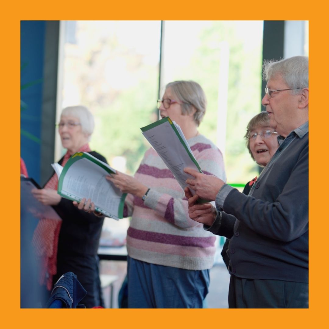 A photo of men and women over 60 singing and holding sheet music