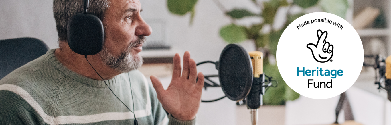 Older man holding hot drink and talking into a microphone for a podcast